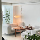 "A minimalist living room featuring a modern wall lamp with a silk shade, providing soft, ambient lighting."