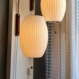 "Two modern wall lamps with luxurious silk shades, creating a warm, ambient glow in a contemporary space."