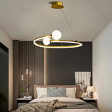 "A gold circular chandelier with two white spherical diffusers, hanging above a bed in a modern bedroom."