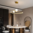 "A gold circular chandelier with two white spherical diffusers, hanging above a round dining table in a modern dining room."