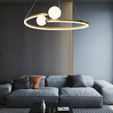"A gold circular chandelier with two white spherical diffusers, hanging above a gray couch in a modern living room."