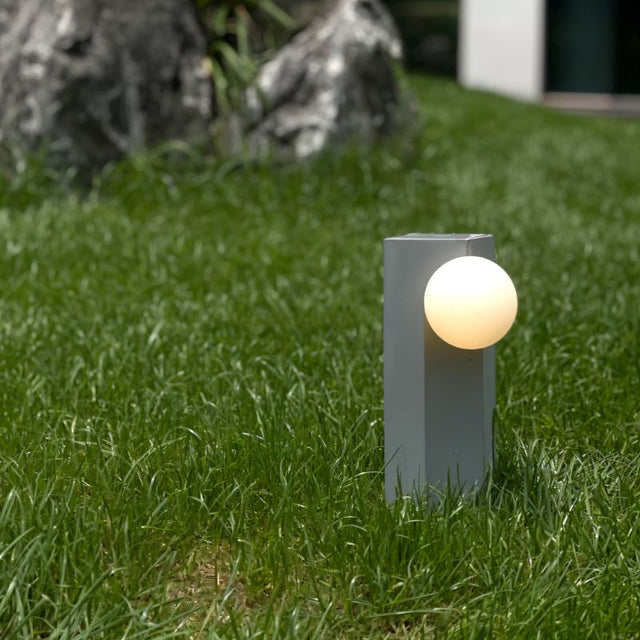 Teral Table Lamp glowing outdoors on grass, showcasing its portable and rechargeable design for ambient lighting in any setting.