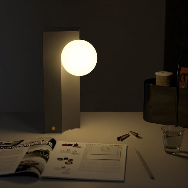 Teral Table Lamp on desk illuminating workspace with warm glow, ideal for modern ambient lighting in home offices or reading areas.
