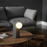 Teral Table Lamp on coffee table in modern living room, providing soft ambient lighting with a sleek concrete and glass design.