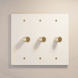 Three-gang white rotary dimmer switch with gold knobs, offering stylish lighting control in modern interiors.