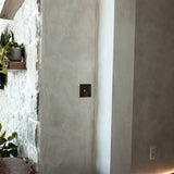 Brass rotary dimmer switch installed on textured wall, blending with rustic interior design in The Brass 3-Way collection.