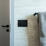 Black rotary dimmer switch installed in a modern bathroom, showcasing The Brass 3-Way Rotary Dimmer Switch in real-life setting.