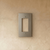 Gray decorator wall plate with rectangular opening and two screw holes on neutral background, angled view.
