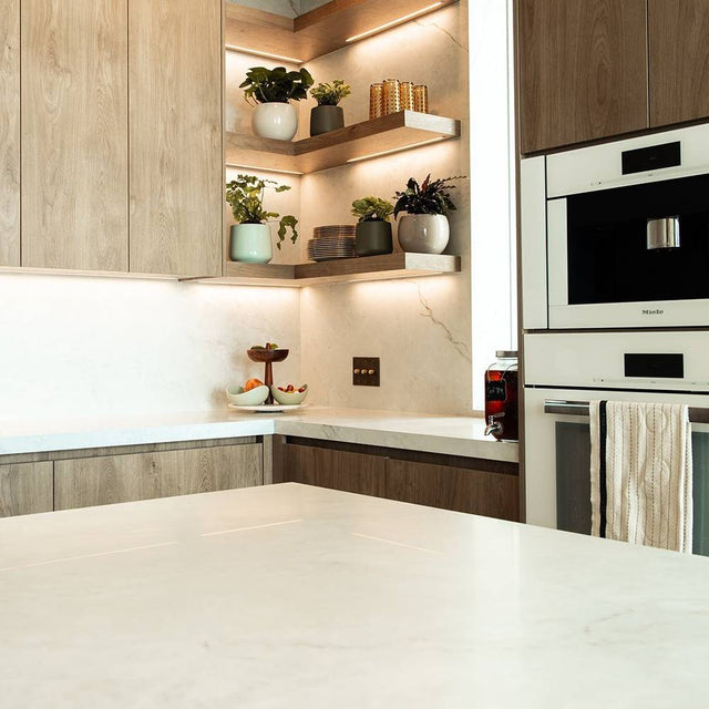 The Brass Dimmer Switch - Open Box installed in a contemporary kitchen with wood cabinetry and under-shelf lighting.