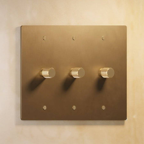 Three-gang The Brass Dimmer Switch - Open Box in brushed brass, featuring elegant knurled knobs for precise light adjustment.