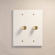 Two-gang The Brass Dimmer Switch - Open Box in white with brass knobs, ideal for bright and modern interiors.