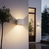"Tine Wall Lamp mounted on an outdoor wall, highlighting the minimalist geometric design with upward and downward beams of light, made from gypsum and aluminum."