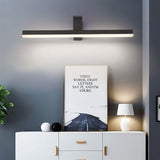 "A modern, dark finish LED vanity light illuminating a living room wall with artwork and furniture."