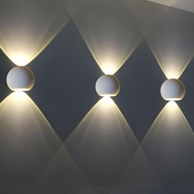 "Triple set of spherical gypsum and aluminum wall lamps, casting soft, multidirectional light, ideal for modern spaces."