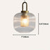 Clear ribbed glass pendant light with brass fixture hanging against cream background.