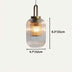 Ribbed glass pendant light with brass fixture and warm glow against cream background.
