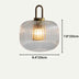 Clear ribbed glass pendant light with brass handle and fittings on neutral background.