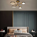 "A modern ceiling light with four circular lights and black metal accents installed above a bed in a room with dark blue walls."