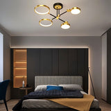 "A modern ceiling light with four circular lights and black metal accents installed in a bedroom with a patterned headboard and dark walls."
