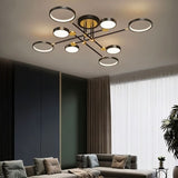 "A modern ceiling light with multiple circular lights and black metal accents installed in a living room with a gray couch and white curtains."