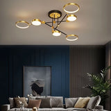"A modern ceiling light with six circular lights and black metal accents installed in a living room with a gray couch and artwork."