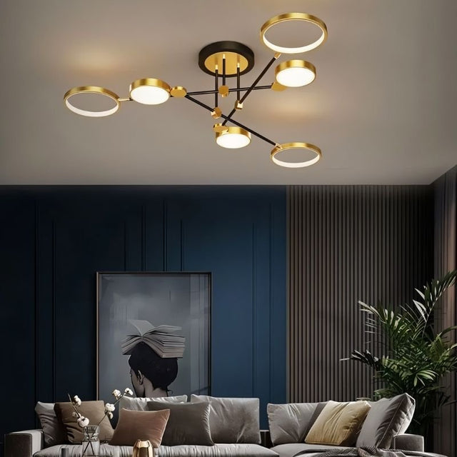 "A modern ceiling light with six circular lights and black metal accents installed in a living room with a gray couch and artwork."