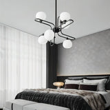 "A modern chandelier with spherical glass shades and a black metal frame in a contemporary bedroom."