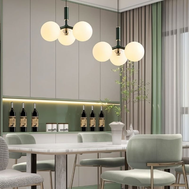 "Two modern pendant lights with three opal glass globes each, in green, hanging over a dining table with upholstered chairs."