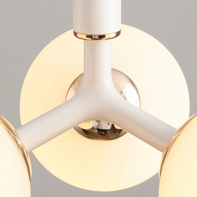 "A close-up view of a modern pendant light with three arms and opal glass globes, showcasing the white and gold finish."