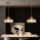  "Two modern crystal pendant lights with gold frames, hanging above a dining table with a marble top and artwork."