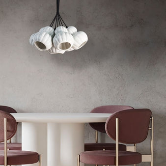 "A modern pendant light with multiple white ceramic shades hangs above a dining table in a contemporary dining room."