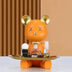 Orange bear figurine with gold ears and nose holding a gold tray of beauty products against a tan and brown background.