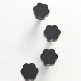 "Set of four black brass floral knobs with brushed finish on a white background."