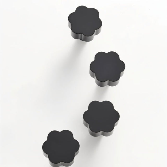 "Set of four black brass floral knobs with brushed finish on a white background."