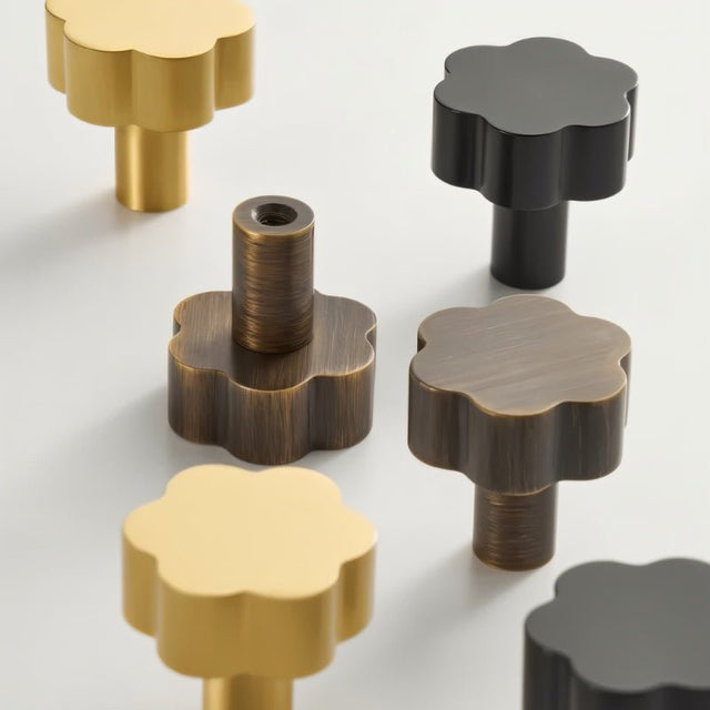 "Angled view of a set of brass floral knobs in gold, black, and bronze with brushed finish."