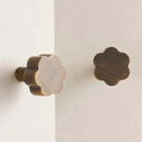 "Two brass floral knobs with brushed finish on a white cabinet."