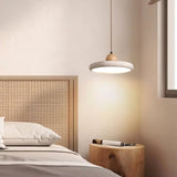 "Modern pendant light with a circular travertine shade and a wooden sphere, hanging over a bedside table in a contemporary bedroom."