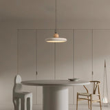 "Modern, minimalist pendant light with a circular travertine shade and wooden sphere, hanging over a round dining table with unique modern chairs in a monochromatic dining room."