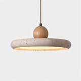 "Modern pendant light with a circular travertine shade and a wooden sphere on top, providing soft, downward lighting over a dining table."
