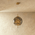 Brass and smoked glass pendant light with warm LED string lights inside, suspended against neutral gray background.