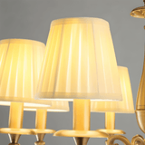 Uloma Chandelier – Elegant Lighting For Luxe Interiors close-up of pleated cloth shades glowing with warm ambient light.