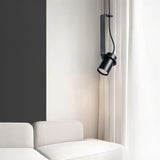 "A black pendant light with a cylindrical shade, suspended in a modern interior, providing focused illumination."
