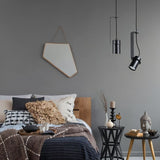 "Two pendant lights with cylindrical shades, one straight and one oblique, illuminating a modern bedroom."