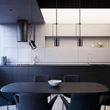 "Pendant lights with cylindrical shades, one oblique and two straight, illuminating a modern kitchen and dining area."