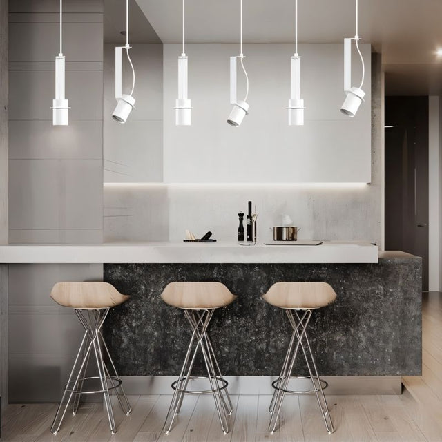 "White pendant lights with cylindrical shades, both straight and oblique, illuminating a modern kitchen island with stools."