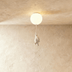 Whimsical ceiling light fixture with three illuminated frosted glass spheres and four hanging white bear figurines against ne