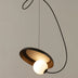 Pendant light with bronze metal shade and glowing white sphere, suspended against neutral background.