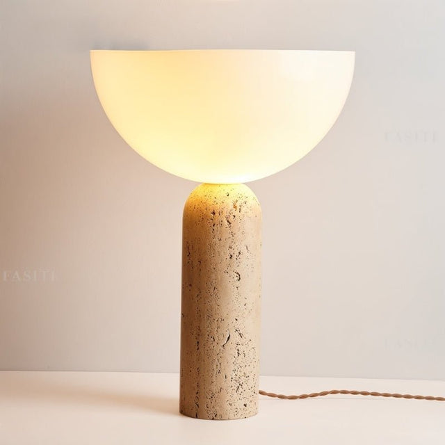 "Elegant table lamp with a travertine cylindrical base and a glowing glass dome shade, creating warm ambient lighting"