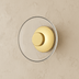 Modern brass and glass circular wall sconce with warm golden light, shown front and side view against white studio background
