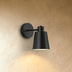 Cowbell-shaped wall sconce with matte black finish shown from front and side views with dimensions on white background.